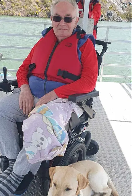 Wheelchair user David with Toby the dog on Floaty the solar-powered boat at Trevassack Lake